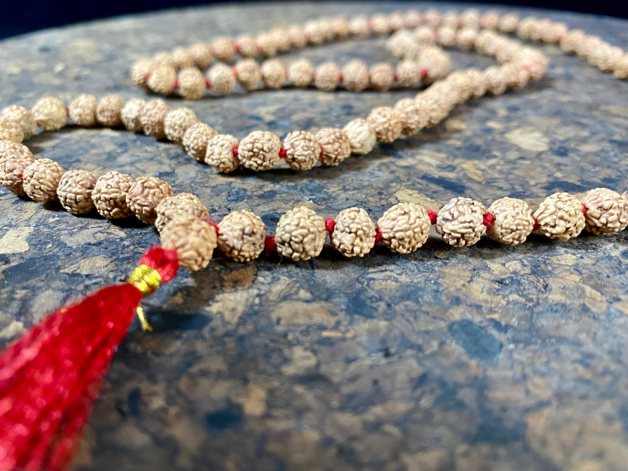 Women or men’s mala necklace, made from small fine rudraksha beads with five mukhi. Knotted between each bead with red thread and finished with a red tassel. As per a standard Buddhist mala, it contains 108 beads. From India