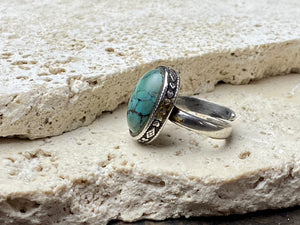 This simple ring features a large antique cabochon turquoise stone, set in a simple patterned silver bezel, with an adjustable ring band. As is the case with many of the rings we are currently buying, the stone is old and has been reset into a new silver band. Measurements: Ring face 2 x 1.5 cm Inner diameter 16.5 mm | Size 6 , however the adjustable band will fit any finger sized 5 -7