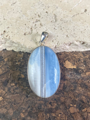 Natural banded blue opal pendants. Set off by sterling silver bezels, topped by generous sized bails large enough to accommodate a thick chain or cord. If you're looking for something a little bit different, this is statement jewellery at its finest.