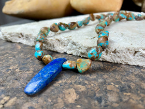Our necklace is crafted from Tibetan turquoise with a central hand carved pendant of lapis lazuli. Finished with sterling silver beads and hook clasp. These beautiful natural stones range in colour from blue to blue-green. Length 42 cm