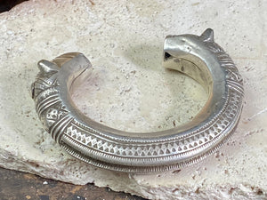 An antique silver cuff, with the ends shaped into the image of a lion's head. Circa early 1900's or earlier, high grade silver. Rajasthan or Himachal Pradesh, India. It has what is most likely the owners mark or initials engraved on it.