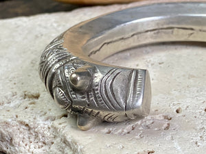 An antique silver cuff, with the ends shaped into the image of a lion's head. Circa early 1900's or earlier, high grade silver. Rajasthan or Himachal Pradesh, India. It has what is most likely the owners mark or initials engraved on it.