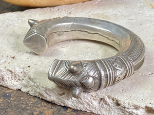 An antique silver cuff, with the ends shaped into the image of a lion's head. Circa early 1900's or earlier, high grade silver. Rajasthan or Himachal Pradesh, India. It has what is most likely the owners mark or initials engraved on it.