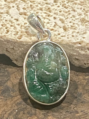 Hand carved from a single high quality translucent emerald and set in a silver surround with silver bail, this oval pendant features a beautifully detailed image of Ganesh.  Height including bail 3.1 cm, width 1.4 cm
