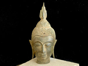 Thai Buddha head. Serene expression, hair topped with the flamed Ushnisha. Sukhothai style, bronze, mid 20th century. A softly contoured face with the bow shaped lips, prominent ears, arched eyebrows and aristocratic features typical of this style of work. Measurements: height 25 cm, width 11 cm