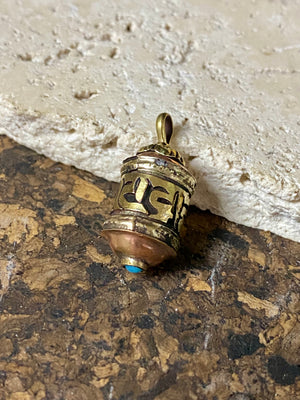 Miniature prayer wheel or prayer box designed to be worn as a pendant, a charm on a bracelet or added to a keyring. Brass and copper, containing a prayer scroll. Height 3 cm. Mantra is Om Mani Padme Hum, prayer to the Compassionate Buddha