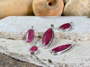 Natural ruby pendants featuring large facet cut stones set in sterling silver. All are set with generous bails to fit on even the largest of chains, torcs or cords. Ranging in length from 6 cm to 2.5 cm