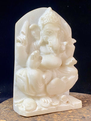 Hand carved marble stone statue of Ganesh. Our Ganesh sits on a lotus pedestal, while his mouse sits at his feet. One of his right hands is upraised in the gesture of protection, while the other holds his favourite ladoo sweet. Measurements: 22 cm high, 14 cm wide, 6 cm depth