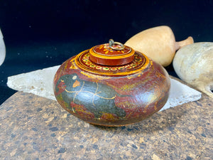 A beautiful low oval lidded bowl or box, traditionally called an opium pot because of its shape. Crafted from wood, then hand painted with hunting scenes. Hand made in Rajasthan, India. Measurements: diameter 14.5 cm, height 7 cm.