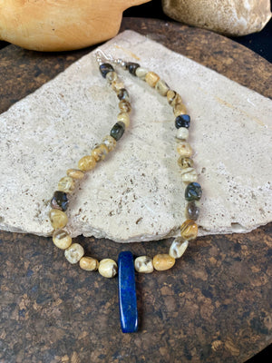A necklace crafted from zebradorite jasper with highlight beads of grey opal and a central hand carved pendant of Afghani lapis lazuli. Finished with sterling silver beads and hook clasp. Our necklace can be worn by either men or women Length 42.4 cm