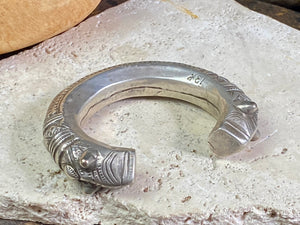 An antique silver cuff, with the ends shaped into the image of a lion's head. Circa early 1900's or earlier, high grade silver. Rajasthan or Himachal Pradesh, India. It has what is most likely the owners mark or initials engraved on it.