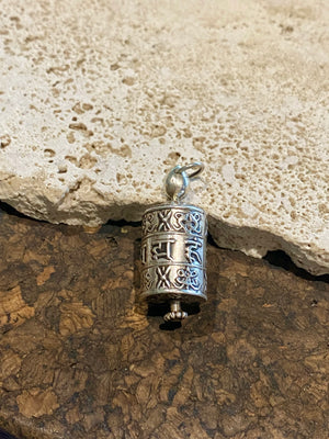 Miniature Buddhist prayer wheel pendant made from sterling silver, covered in images of the eight auspicious symbols and the mantra Om Mani Padme Hum. Prayer scroll inside.  Height 4 cm