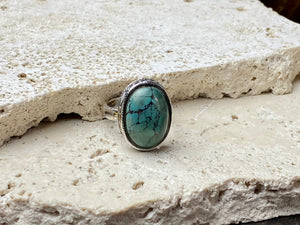 This simple ring features a large antique cabochon turquoise stone, set in a simple patterned silver bezel, with an adjustable ring band. As is the case with many of the rings we are currently buying, the stone is old and has been reset into a new silver band. Measurements: Ring face 2 x 1.5 cm Inner diameter 16.5 mm | Size 6 , however the adjustable band will fit any finger sized 5 -7