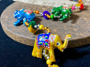 <p>Elephants on strings. Hand painted paper mache elephants, all in different colours. Bell at base, colourful wood beading, cotton pom poms, large loop at the top for hanging. Great gift for kids but really, just perfect to add a touch of colur and Indian styling to any home.</p> <p><strong>Measurements</strong>: Total length 81 cm, elephants are width 6 cm</p>