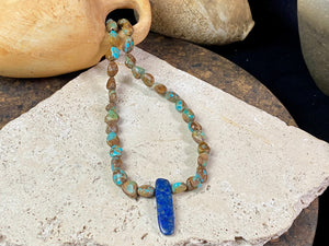 Our necklace is crafted from Tibetan turquoise with a central hand carved pendant of lapis lazuli. Finished with sterling silver beads and hook clasp. These beautiful natural stones range in colour from blue to blue-green. Length 42 cm