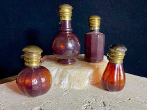 Small cranberry glass perfume bottles with hinged flip top brass lids. 