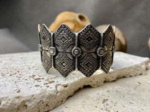 A modern interpretation of an antique style of bracelet, this piece is hand crafted from sterling silver by Rajasthani silversmiths. Exquistely detailed, the oxidised finish shows off the workmanship beautifully. There is some room for movement in this cuff, and it is designed to fit an average sized wrist.  Measurements: Inside opening is 6.5 cm, with room for expansion or contraction
