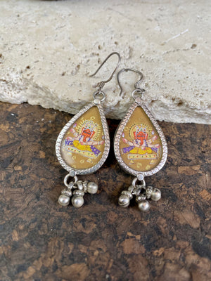 Exquisite miniature hand painted earrings featuring Ganesh seated, set within sterling silver frames, backed with decorated silver and set with a silver dangles bail at the base. Bought from the artist who painted them in India, then set into silver. Measurements: 6 cm (2.35") height including hooks or 2 cm at widest point