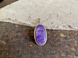 This lustrous charoite pendant is set off by a sterling silver bezel, topped by a bail that’s large enough to accommodate a thick chain or cord. A stunning piece of purple charoite with deep colour. Measurements: 5.2 cm (2 in) height including bail, 2.2 cm (0.75 in) at widest point