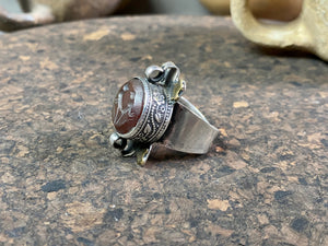 Afghani ring features a large carnelian stone carved with the images of two birds. Medallions of brass, silver loops and an embossed band complete the decoration. This large silver ring sits high on the finger and is statement jewellery. Adjustable ring, inner diameter 18 mm | Size 7.75 | No 17