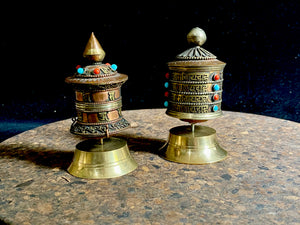 Handmade in Nepal from brass and copper, these small standing prayer wheel are weighted for spinning and contain a scroll on which is printed the mantra "Om Mani Padme Hum", a prayer to the Compassionate Buddha, written many times over. Two styles.  Measurements: height 9 cm