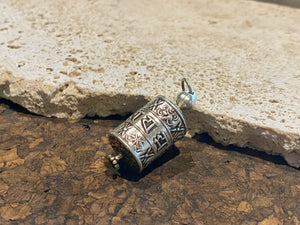 Miniature Buddhist prayer wheel pendant made from sterling silver, covered in images of the eight auspicious symbols and the mantra Om Mani Padme Hum. Prayer scroll inside.  Height 4 cm