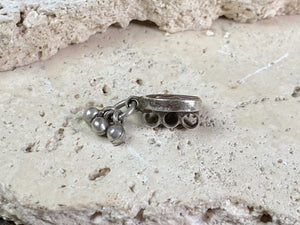 This old amulet represents the female principal through its depiction of the yoni or gauri-patta. The channel once held enamel and the central stone has been replaced at some time recently. Early 20th century. High grade silver, from northern India. This is a beautiful, old amulet with history. Height 2.5 cm including dangles, height of pendant 1.4 cm, width 1.3 cm