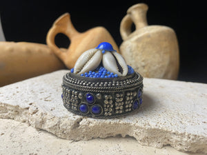 Small round pill or trinket boxes. Metal with bead and cowrie shell decoration. Tight fitting lid. Velvet lined, including inside the lid. These are perfect trinket boxes for kids, and would also make a very nice jewellery presentation box for gifting jewellery.  Measurements: 5.5 cm (2.25") diameter, height 5 cm (2")