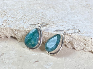 Our beautiful teardrop emerald earrings feature large facet cut emeralds of a deep variegated green colour. They are set in a sterling silver shadow box mount to highlight their beauty. measurements 3.6 cm length including hook.