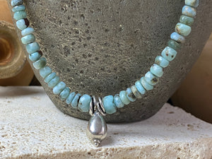 Light blue blue necklace of tumbled, facet cut graduated larimar, highlighted with Rajasthani silver beads and a beautiful central drop pendant. Finished with sterling silver findings and hook clasp. and a hook clasp. Measurements: 46 cm (18") length