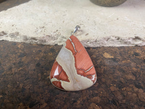 A unique pendant carved from a single piece of jasper intertwined with moonstone. A sterling silver bezel and generous bail completes this statement pendant. Open at the back to allow the stone to touch the skin. Measurements: height 6.8 cm including bail (2.75"), width 4 cm at widest point