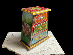 This intricately hand painted box features three drawers and small feet. Brass knobs as handles add a touch of elegance, perfect for holding everything from trinkets to jewellery. Width 21.5, depth 11.5 cm, height 24 cm