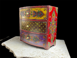 This brightly painted box features three spacious drawers, a curved front and small feet. Brass knobs as handles add a touch of elegance to our storage chest, perfect for holding everything from trinkets to jewellery and essential oils. From Rajasthan, India. Width 23.5, depth 13 cm, height 23 cm