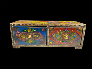 This intricately painted box features two spacious drawers, small feet and brass knobs as handles. The roominess of the drawers means our long, low chest is perfect for holding everything from trinkets to jewellery and keys. A lovely, hand painted piece of craftsmanship from Rajasthan, India.
Measurements: width 24, depth 9 cm, height 9 cm
