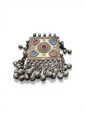Antique Hunza Valley Uzbek pendant consisting of a flat, double skinned rectangular plaque with a central flower design surrounded by 4 stylised leaves, set with blue and red foil backed glass. Small bells hang in a fringe from the base of the pendant and the sides. Silver and faint gilding. Height 7.4 cm