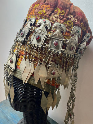 Ersari headdress consisting of a metal gaashbaagh & a high embroidered conical hat into which it attached with long spikes. The cap is quilted cotton covered in velvet and detailed silk embroidery. An heirloom piece, dating from 1870-1890. Cap height 23 cm. Tiara: width 53 cm, height of band 7 cm, side dangles 44 cm