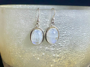 Simple and elegant, these oval rainbow moonstone earrings feature cabochon cut rainbow moonstones and are finished with detailed sterling silver surrounds and very generous shepherd hooks. Measurements: height 3.2 mm (0.13 in) including hook, width 1.3 cm