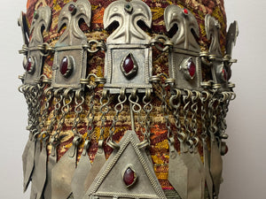 Ersari headdress consisting of a metal gaashbaagh & a high embroidered conical hat into which it attached with long spikes. The cap is quilted cotton covered in velvet and detailed silk embroidery. An heirloom piece, dating from 1870-1890. Cap height 23 cm. Tiara: width 53 cm, height of band 7 cm, side dangles 44 cm