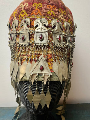 Ersari headdress consisting of a metal gaashbaagh & a high embroidered conical hat into which it attached with long spikes. The cap is quilted cotton covered in velvet and detailed silk embroidery. An heirloom piece, dating from 1870-1890. Cap height 23 cm. Tiara: width 53 cm, height of band 7 cm, side dangles 44 cm