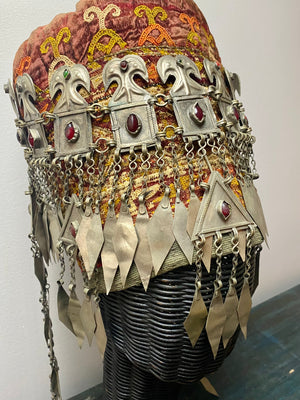 Ersari headdress consisting of a metal gaashbaagh & a high embroidered conical hat into which it attached with long spikes. The cap is quilted cotton covered in velvet and detailed silk embroidery. An heirloom piece, dating from 1870-1890. Cap height 23 cm. Tiara: width 53 cm, height of band 7 cm, side dangles 44 cm