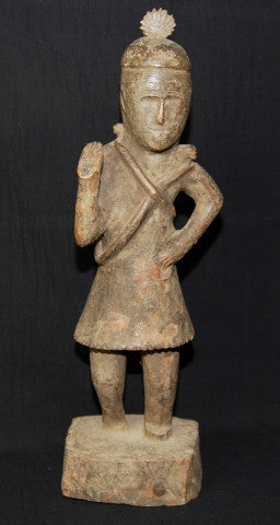 Naga antique tribal statue, an ancestor figure with right hand raised in protection, head adorned with plumed cap. Two snakes are wrapped around the torso, their heads resting on the shoulders, dressed in a fringed kirtle. 19th C or earlier, well preserved with an aged patina. Height 56 cm, width 16.5 cm, depth 15 cm