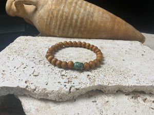 Sandalwood Buddha bracelet. Women or men’s bracelet made from sandalwood features a detailed solid brass Buddha bead. On elastic cord. Our mala bracelet will fit small men's wrists, and sit well on a women's wrist. 18 cm inside circumference. Sandalwood beads are 6 mm diameter, Buddha bead is 1 cm in length