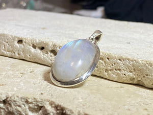 Oval high cut rainbow moonstone pendant set in sterling silver with a generous flexible bail to take a large chain or cord. A high quality stone with blue colour and fire.