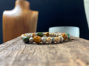 Stretchy bracelet featuring hand carved yak bone skulls, natural antique Tibetan turquoise, undyed howlite , carved lotus root and sterling silver beads. Designed to fit on a wrist 11-14 cm circumference