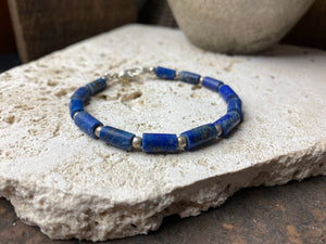 Lapis lazuli bracelet consists of hand cut tubes of dark blue natural matched, graduated lapis tube beads. Finished with sterling silver ball spacer beads and a sterling silver clasp