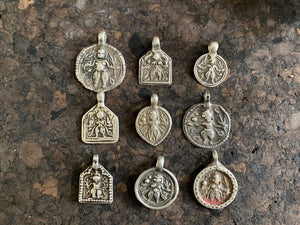 Antique silver amulets representing the Hindu god Kali, in her protective form, and dating from the early 19th - early 20th century. Measurements: all vary between 1.5 and 2.2 cm in width