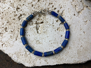 Lapis lazuli bracelet consists of hand cut tubes of dark blue natural matched, graduated lapis tube beads. Finished with sterling silver ball spacer beads and a sterling silver clasp