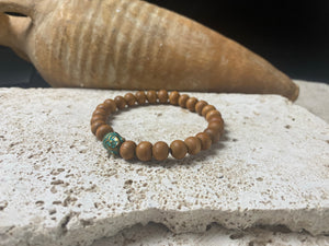 Sandalwood Buddha bracelet. Women or men’s bracelet made from sandalwood features a detailed solid brass Buddha bead. On elastic cord. Our mala bracelet will fit small men's wrists, and sit well on a women's wrist.  18 cm inside circumference. Sandalwood beads are 6 mm diameter, Buddha bead is 1 cm in length