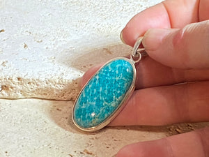 This unusual blue amazonite pendant is set off by a sterling silver bezel, topped by a bail that’s large enough to accommodate a thick chain or cord. A stunning piece of amazonite with a very unusual colour.