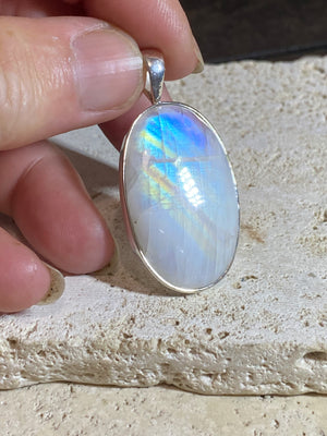 Large oval rainbow moonstone pendant set in sterling silver with a generous bail to take a large chain or cord. A beautiful stone with light blue, green and orange colour.